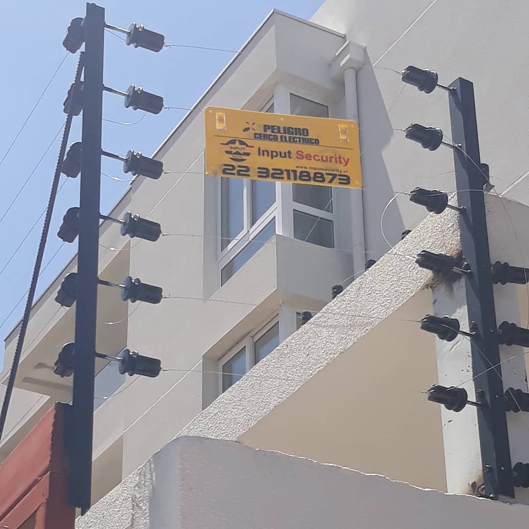 Cierre eléctrico perimetral en condominio con reja metálica y postes de seguridad